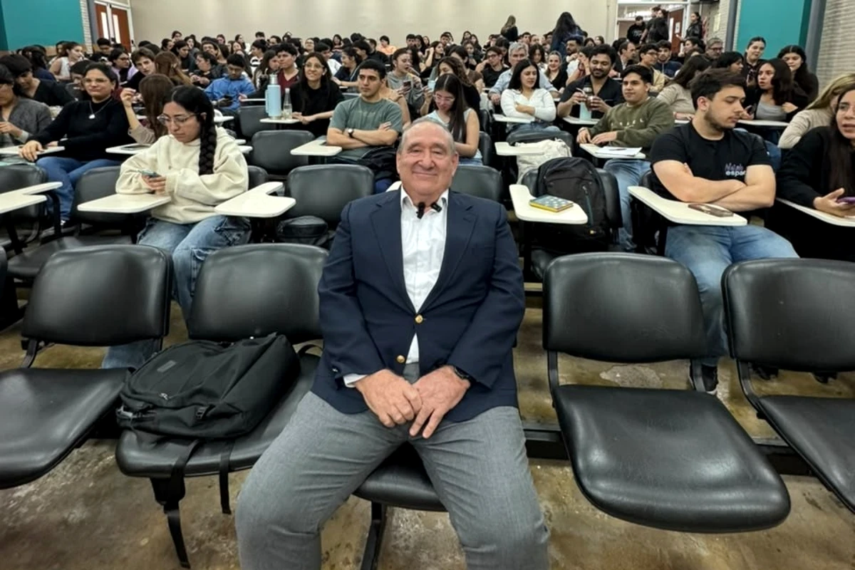Dr. Alfonso Verdugo junto a estudiantes en el auditorio universitario